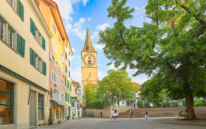 Zürich city square with St. Peter's Church tower and colorful buildings.