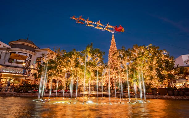 Dancing Fountain at the Grove Los Angeles with holiday lights and Santa sleigh overhead.
