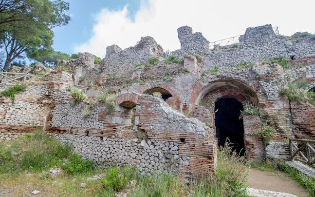 Villa Jovis ruins with stone arches and greenery, Capri, Italy.