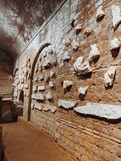 Ancient Roman catacombs with stone carvings on brick walls, part of the Underground Rome Catacombs Tour.