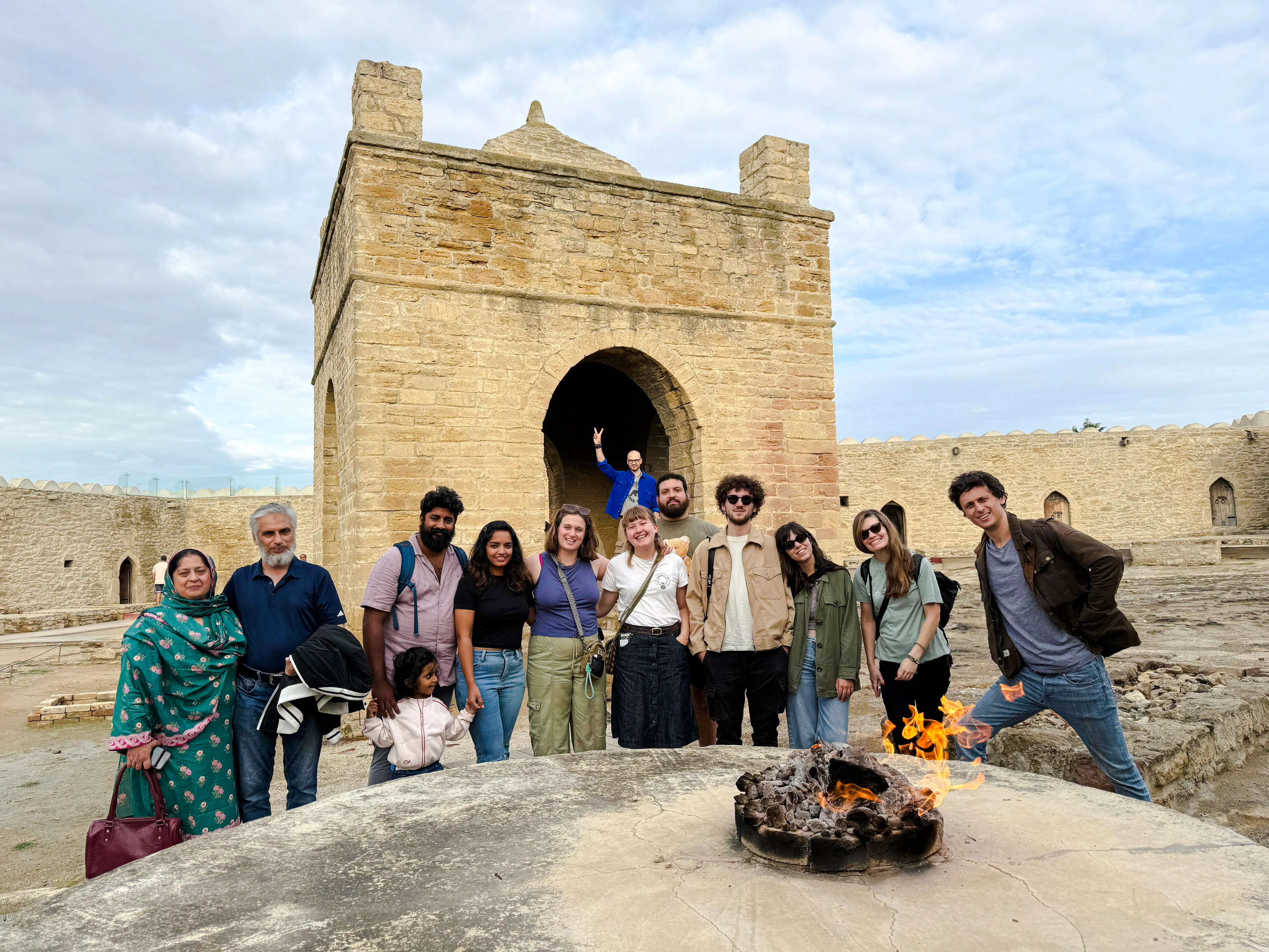 Group at Ateshgah Fire Temple, Baku, with flames in foreground during Gobustan & Absheron tour.