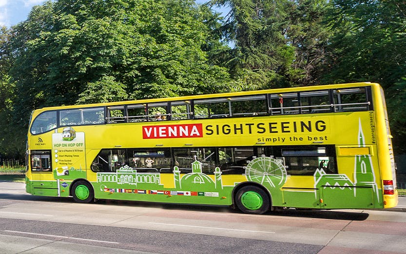 Vienna sightseeing hop-on hop-off bus on a tree-lined street.