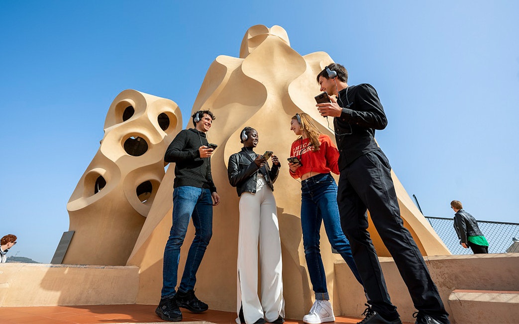 Visitors with audio guides at La Pedrera-Casa Milà rooftop in Barcelona.