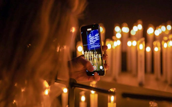 Person photographing candlelit scene with phone at Mythos Mozart event.