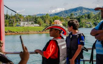 Boat ride on Guatapé reservoir with children in life jackets and scenic view.