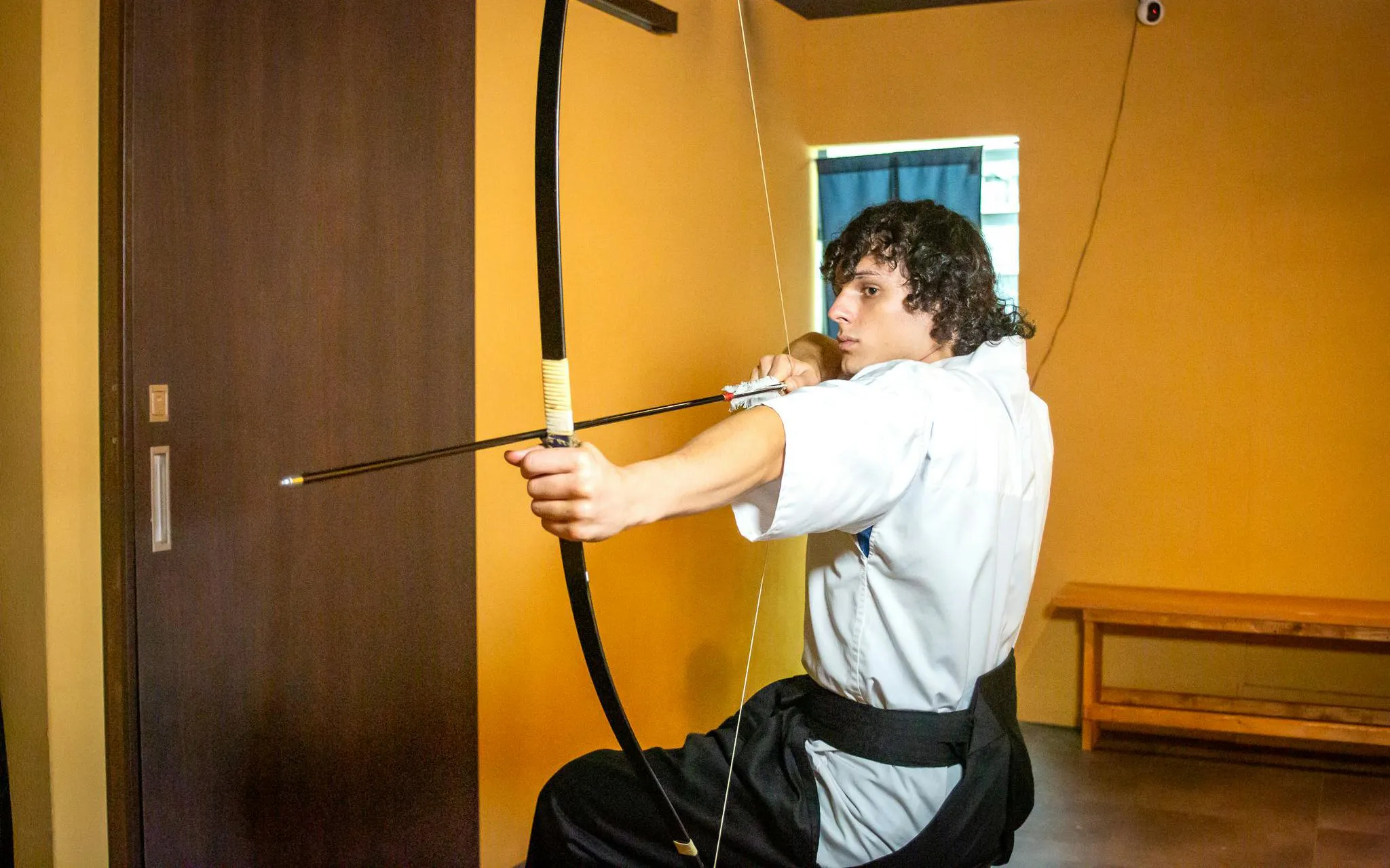 Japanese archery participant aiming bow during 20-arrow experience in Kyoto.