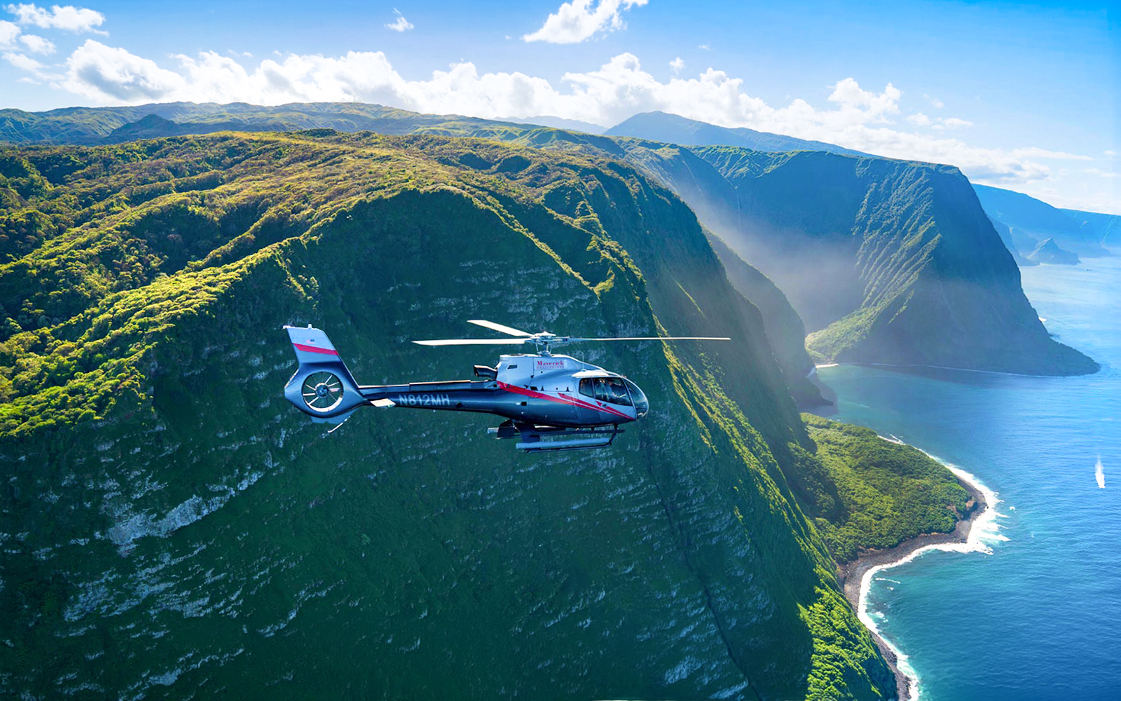 Helicopter flying over lush cliffs and ocean in Maui, Hawaii.