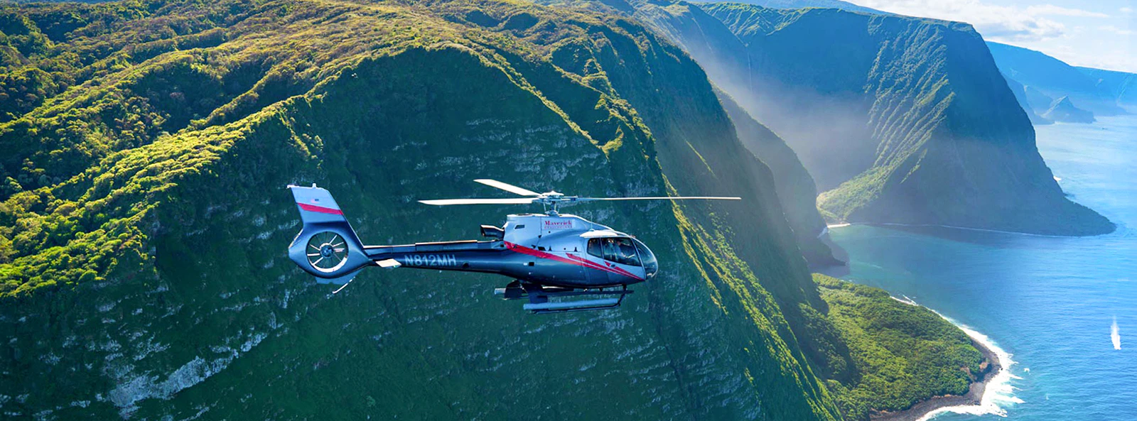 Helicopter flying over lush cliffs and ocean in Maui, Hawaii.