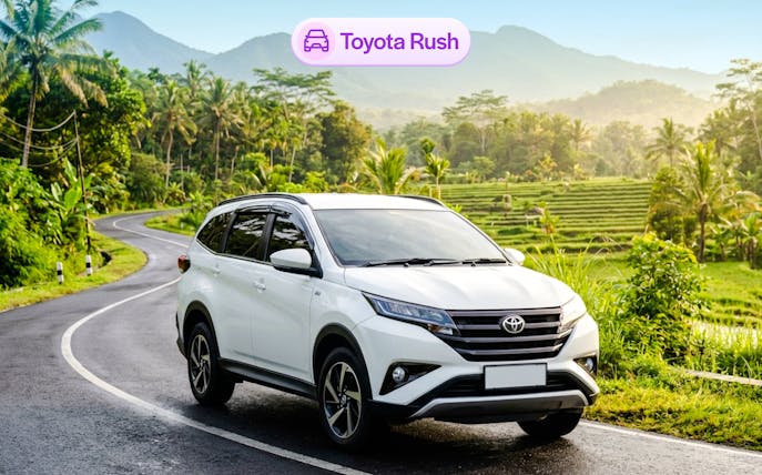 Toyota Rush rental car on scenic Bali road with rice terraces.