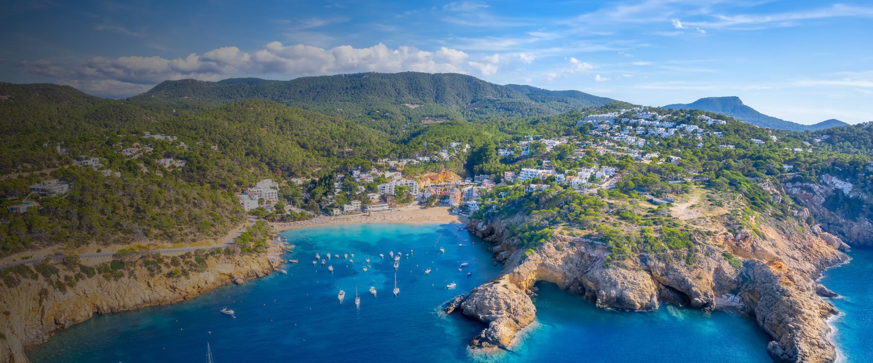 Aerial view of Cala Vadella beach with boats in Ibiza, Spain.