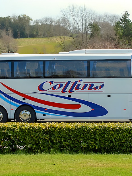 Tour coach parked in a scenic countryside setting.