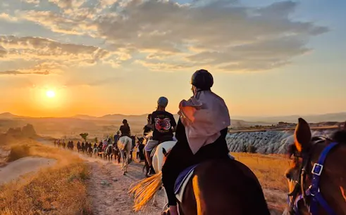 Horseback riders on a trail at sunrise in Cappadocia, Turkey.
