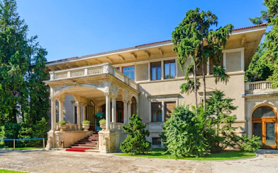 Ceausescu Mansion exterior with grand entrance and lush greenery.