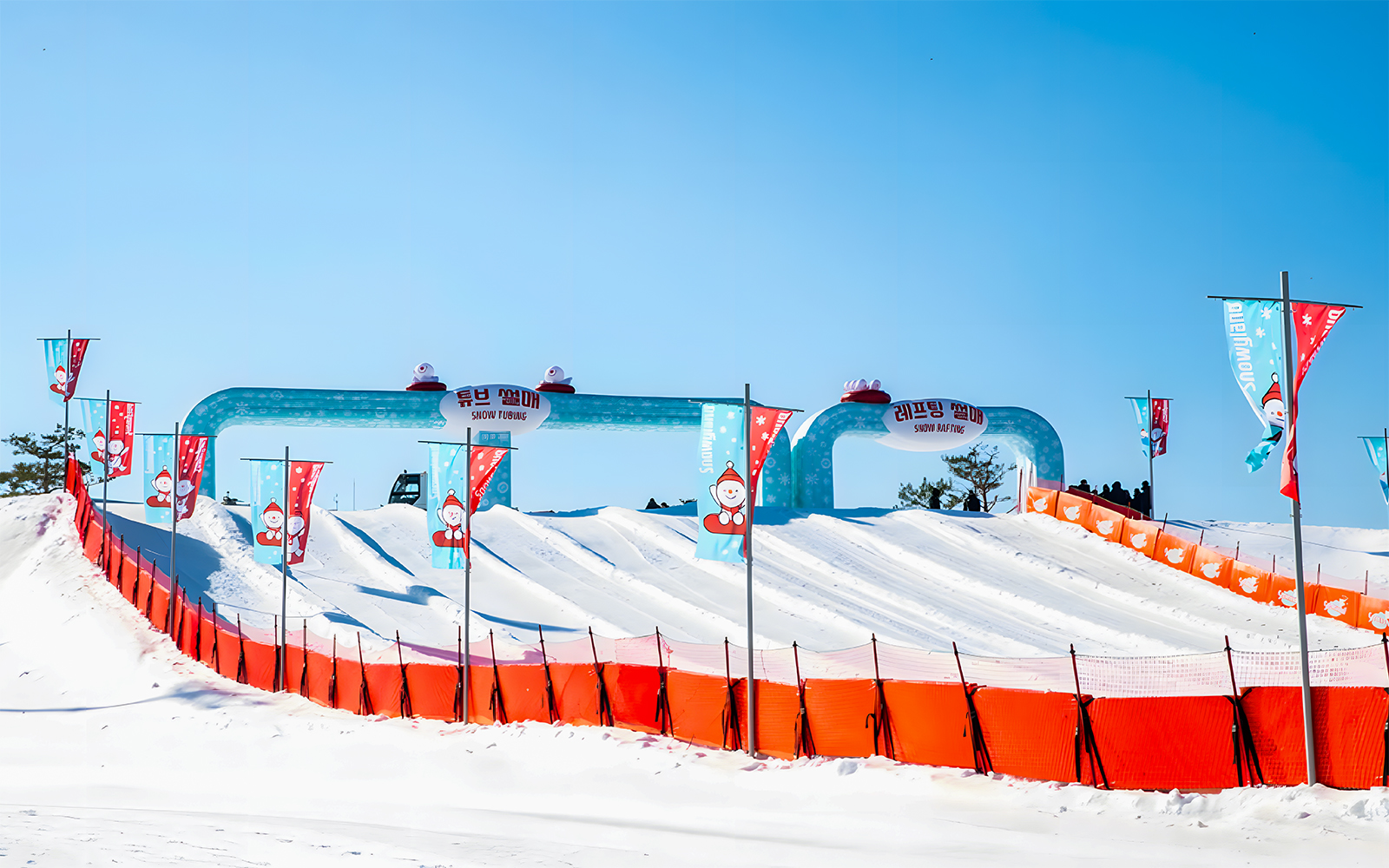 Snow tubing lanes at Vivaldi Park Snowy Land, South Korea, with colorful flags.