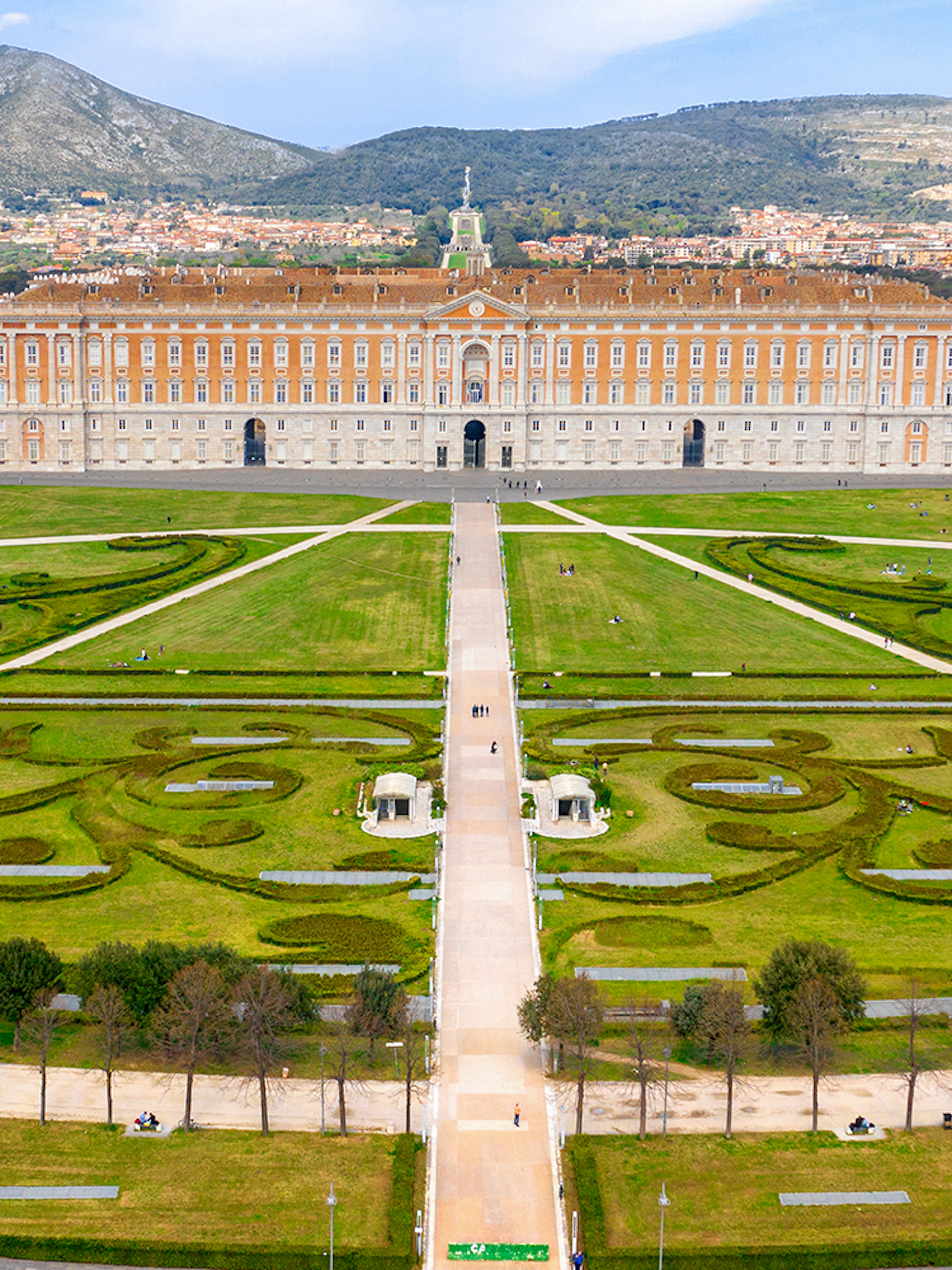 Royal Palace of Caserta with expansive gardens and mountain backdrop.