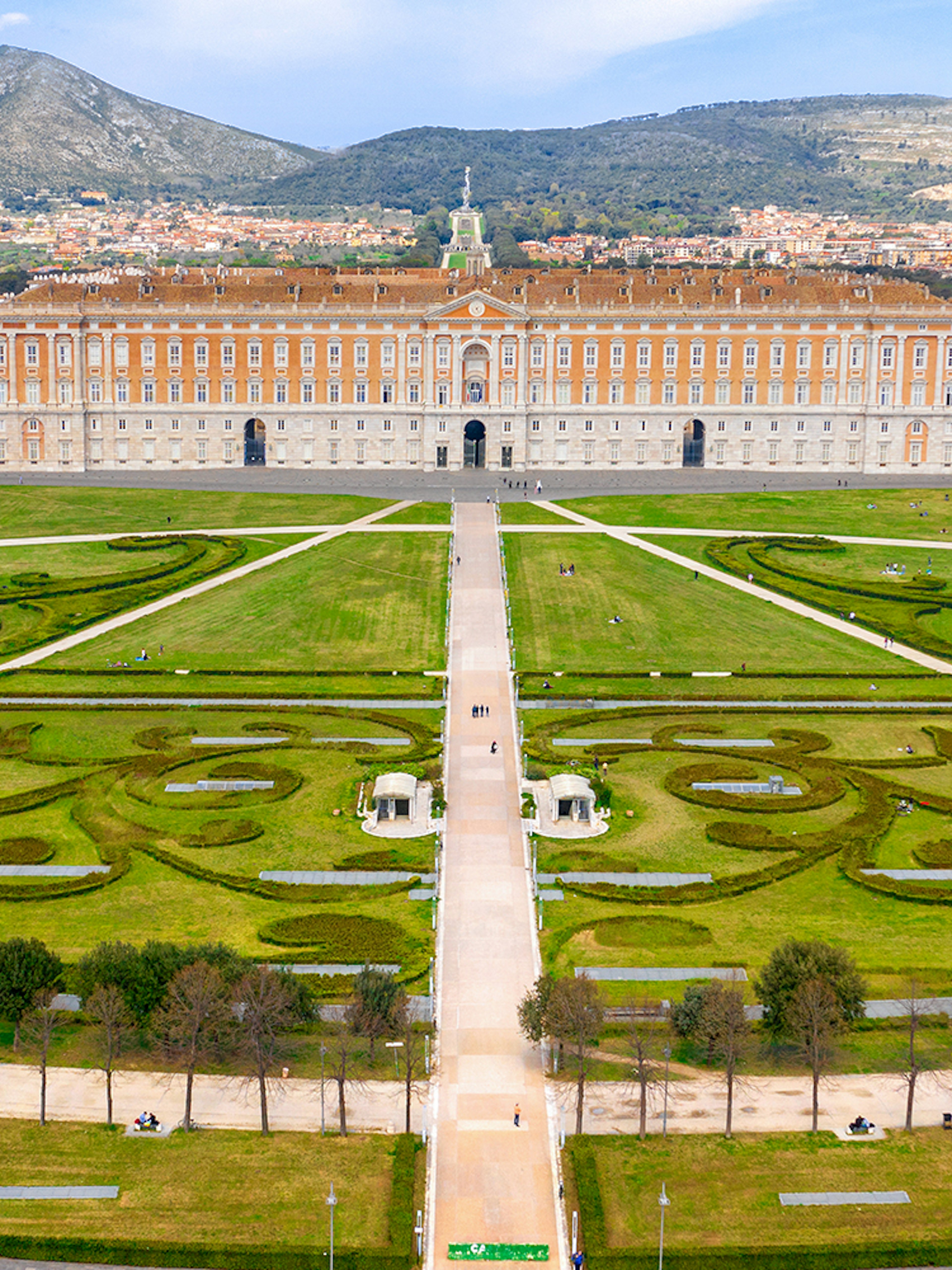 Royal Palace of Caserta with expansive gardens and mountain backdrop.
