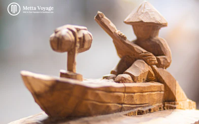 Wood carving of a person in a boat at Driftwood Village, Hoi An workshop.