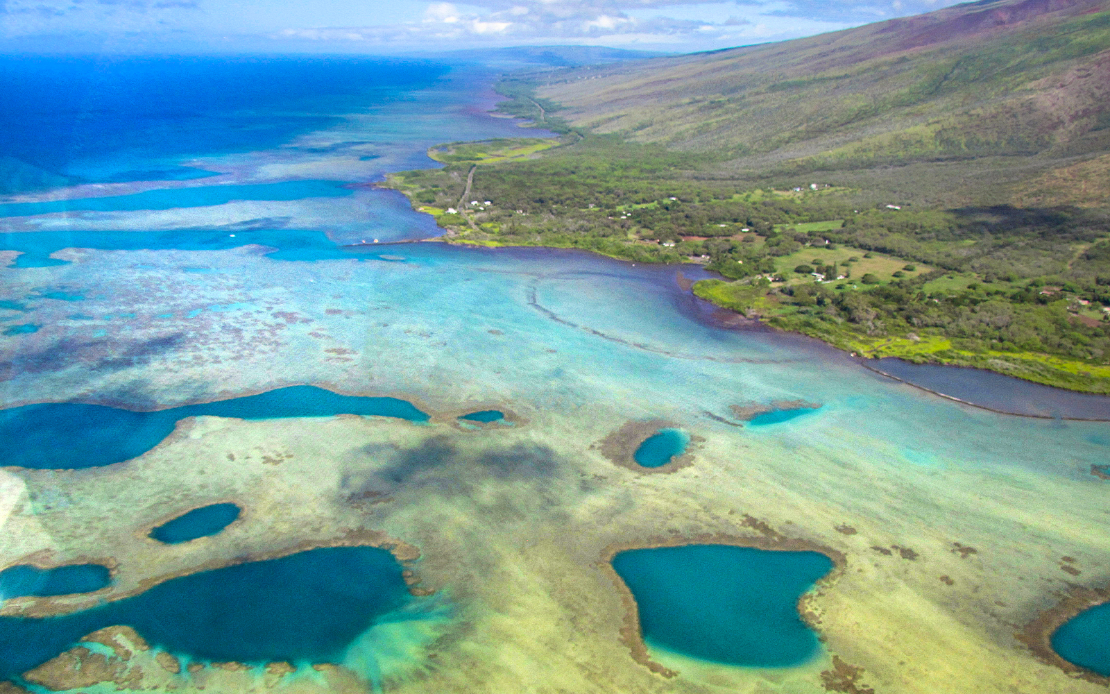 Aerial view of Maui coastline with turquoise waters and lush greenery during a helicopter tour in Hawaii.