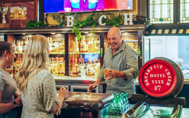 Bartender serving drinks at the Breakfast Creek Hotel bar in Brisbane.