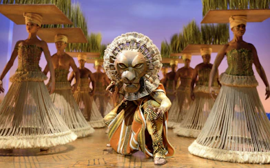 Lion King performers in traditional costumes on West End stage.