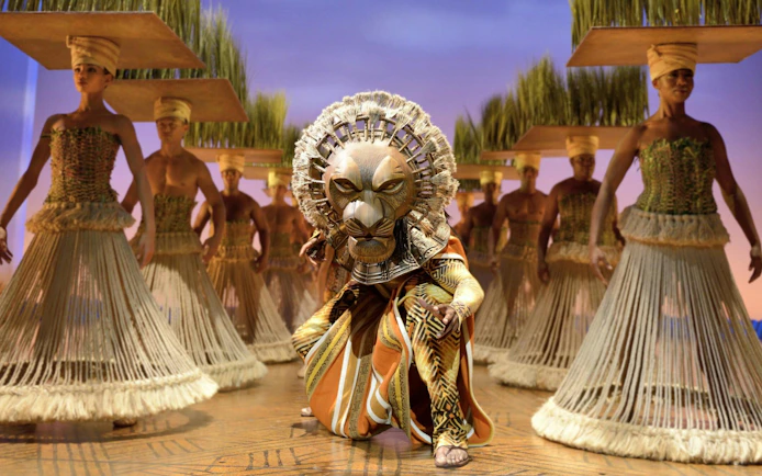 Lion King performers in traditional costumes on West End stage.