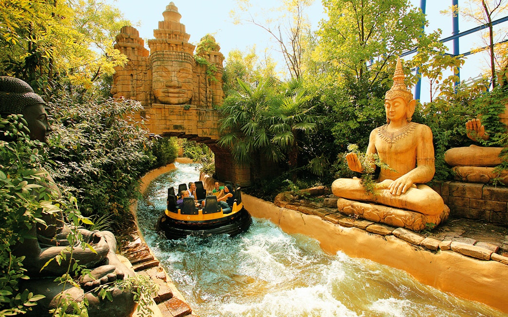 Raft on rapids passing statues and temple facade at Gardaland Park.