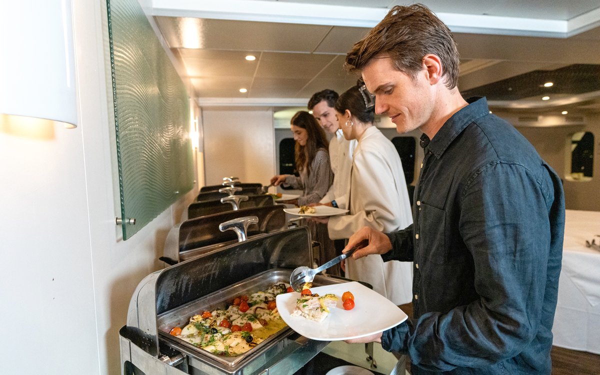 Guests serving from a buffet on a luxury catamaran cruise in Sydney.