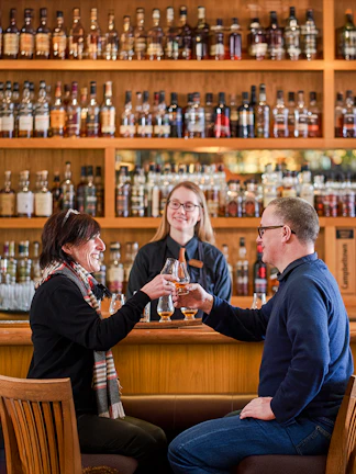 Couple toasting whisky glasses at a bar during The Gold Tour - Scotch Whisky Experience.