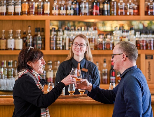 Couple toasting whisky glasses at a bar during The Gold Tour - Scotch Whisky Experience.