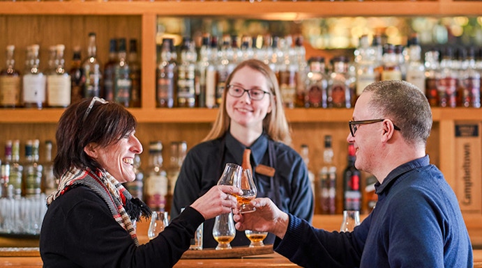 Couple toasting whisky glasses at a bar during The Gold Tour - Scotch Whisky Experience.