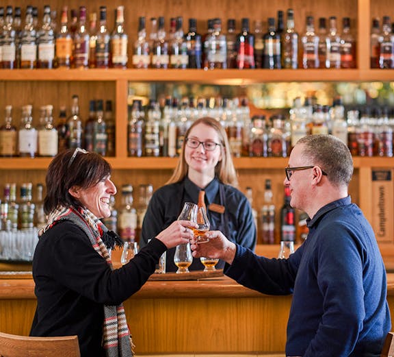 Couple toasting whisky glasses at a bar during The Gold Tour - Scotch Whisky Experience.
