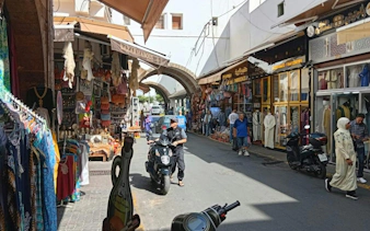 Bustling market street in Marrakech with shops and people, part of Casablanca day trip.