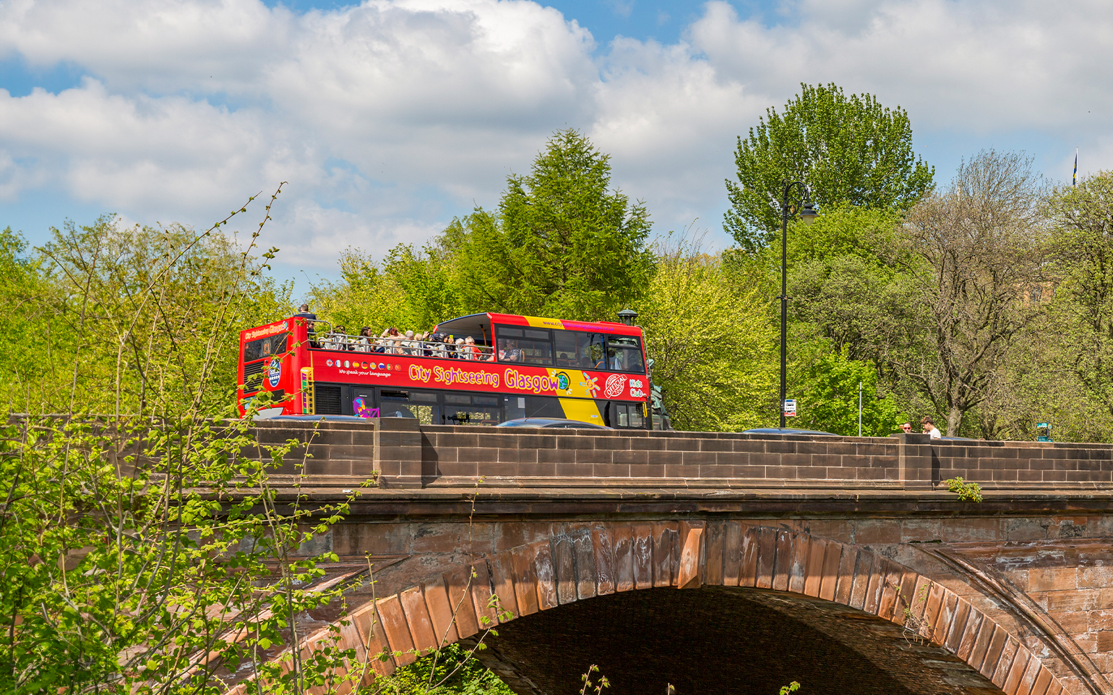 Open-top sightseeing bus crossing a bridge in Glasgow.