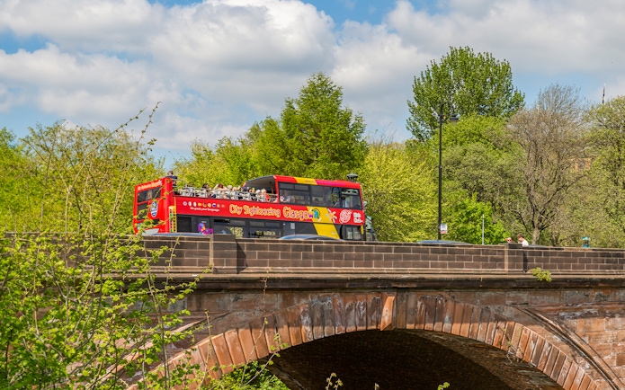 Open-top sightseeing bus crossing a bridge in Glasgow.