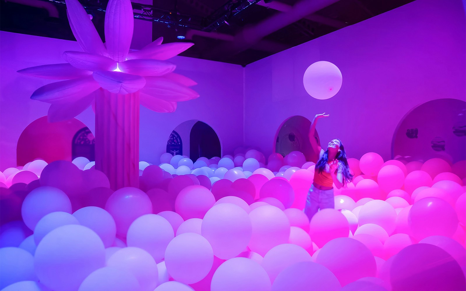 Person enjoying a room filled with colorful balloons at Bubble Planet New Jersey.