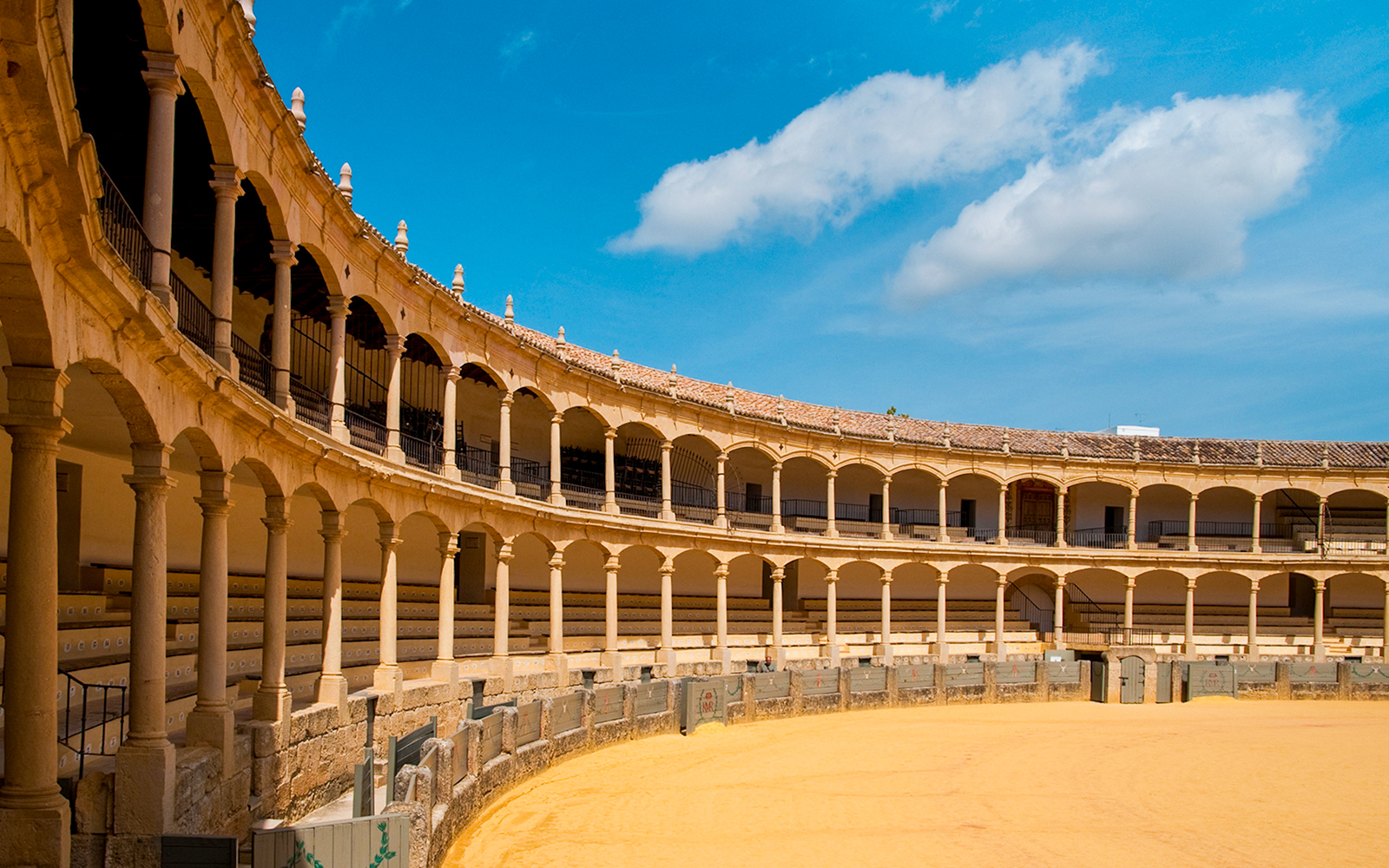 Plaza de Toros de Ronda interior with arched seating and sandy arena.