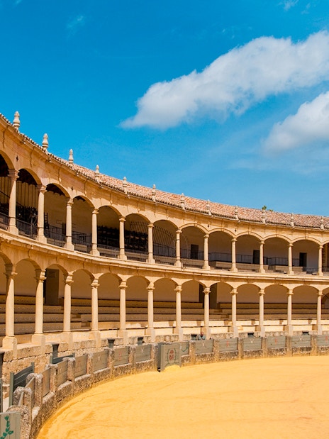 Plaza de Toros de Ronda interior with arched seating and sandy arena.
