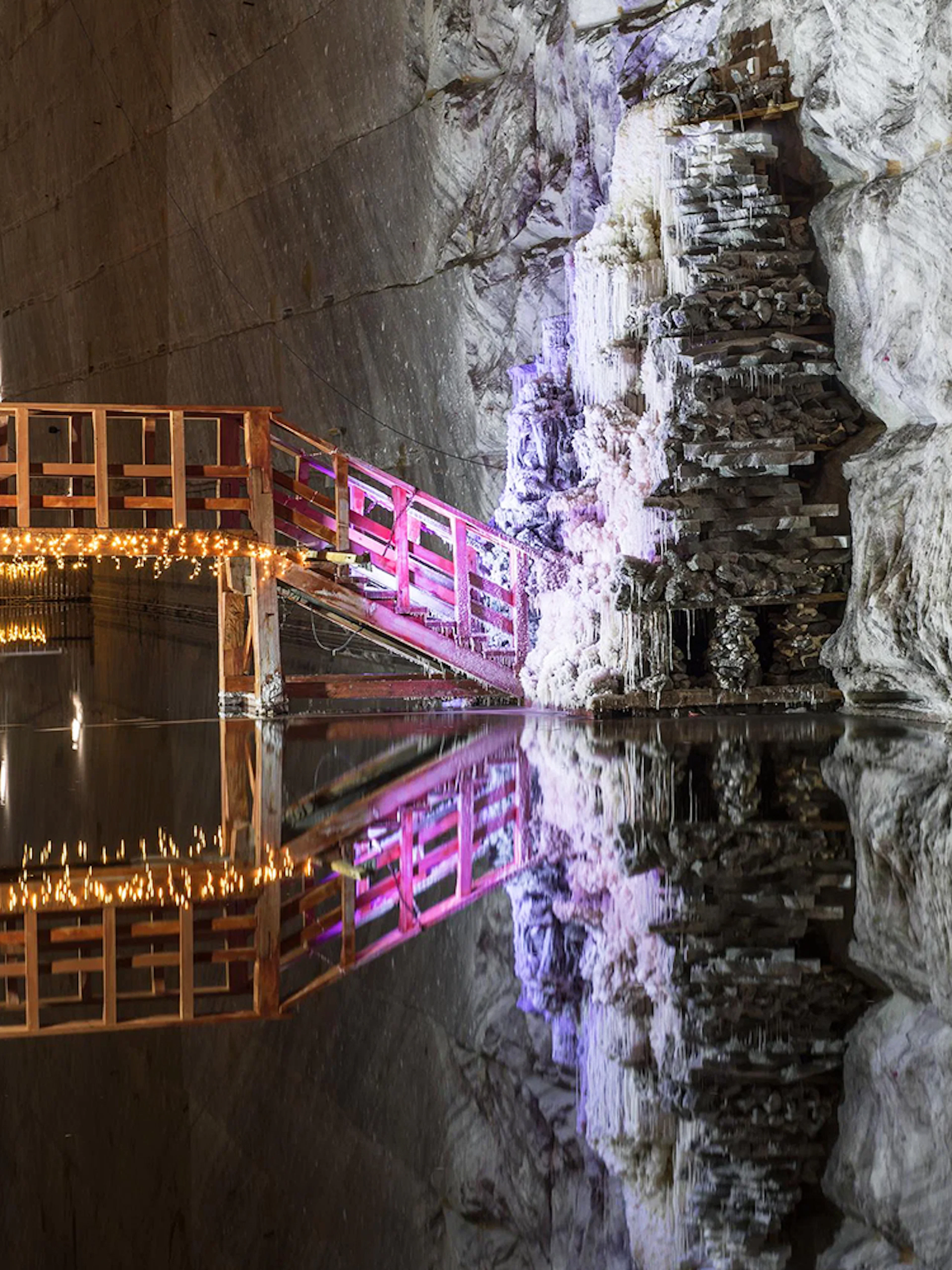 Wooden bridge with lights over water in Slanic Prahova Salt Mine, Bucharest.