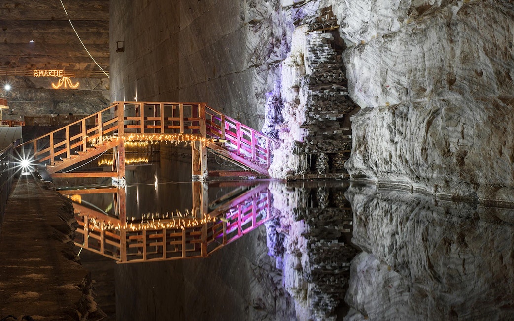 Wooden bridge with lights over water in Slanic Prahova Salt Mine, Bucharest.