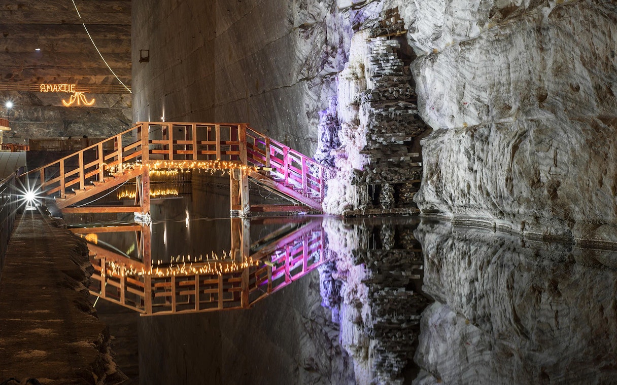 Wooden bridge with lights over water in Slanic Prahova Salt Mine, Bucharest.