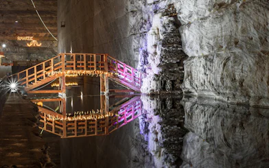 Wooden bridge with lights over water in Slanic Prahova Salt Mine, Bucharest.
