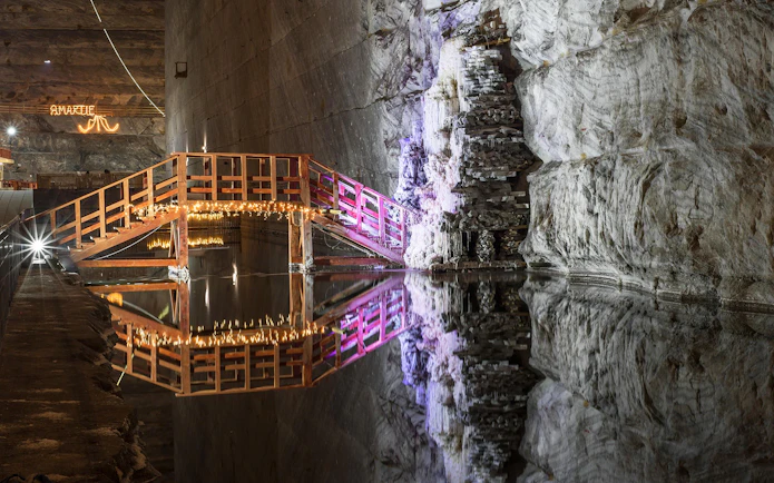 Wooden bridge with lights over water in Slanic Prahova Salt Mine, Bucharest.