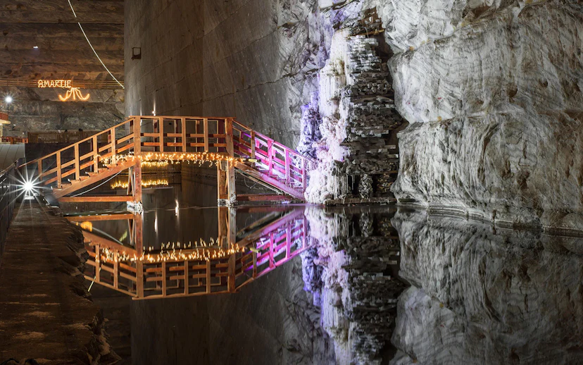 Wooden bridge with lights over water in Slanic Prahova Salt Mine, Bucharest.