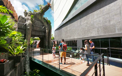 Visitors walking on a bridge at Aquaria Phuket entrance, surrounded by lush greenery.
