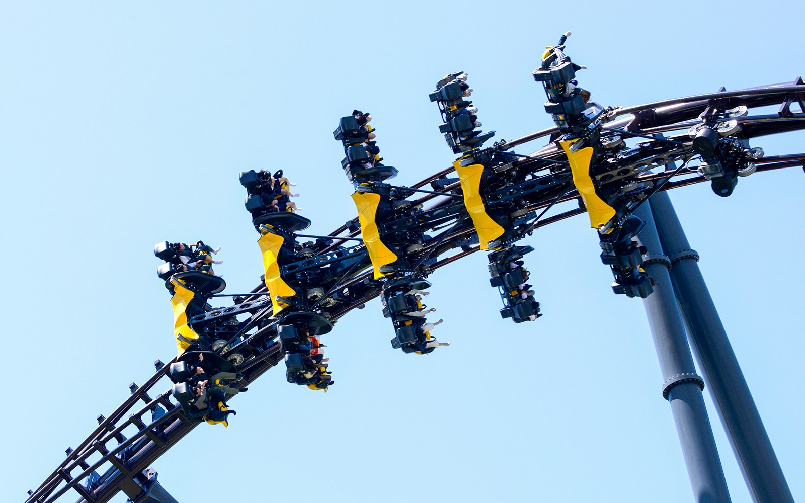 Roller coaster with riders upside down on a loop at an amusement park.