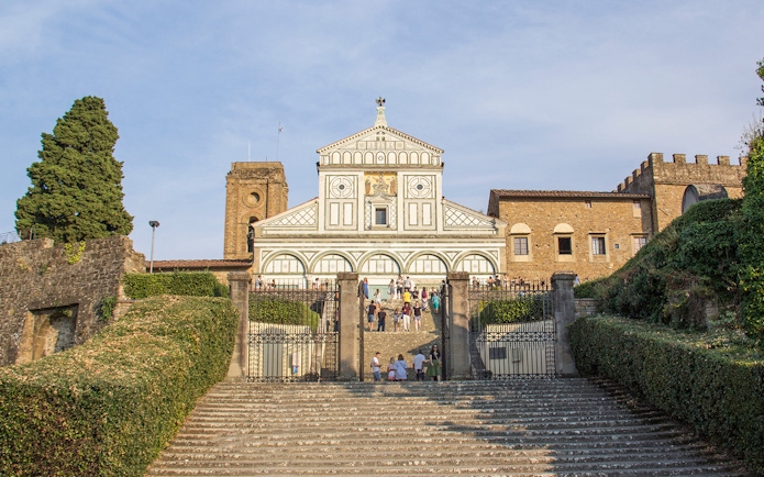 San Miniato al Monte facade in Florence, Italy, with visitors on steps.
