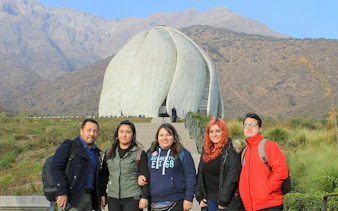 Tourists in front of Baháʼí House of Worship, Santiago, with Andes Mountains backdrop.