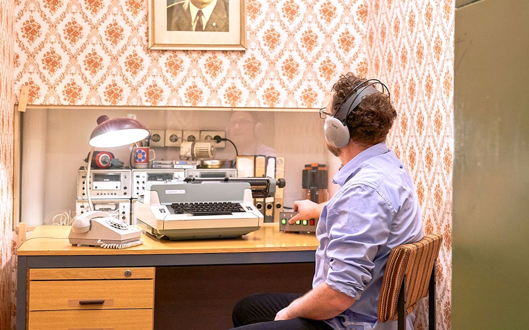 Man using vintage typewriter and equipment at DDR Museum Berlin.