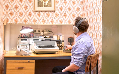 Man using vintage typewriter and equipment at DDR Museum Berlin.