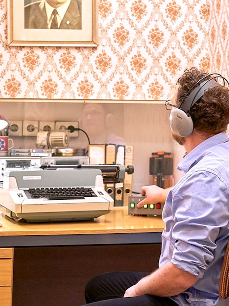 Man using vintage typewriter and equipment at DDR Museum Berlin.
